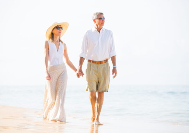 Middle Age Couple Walking Along Beach