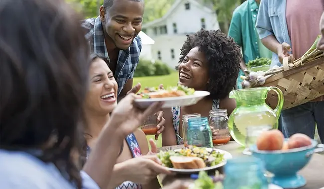 people smiling around picnic table with food on the table