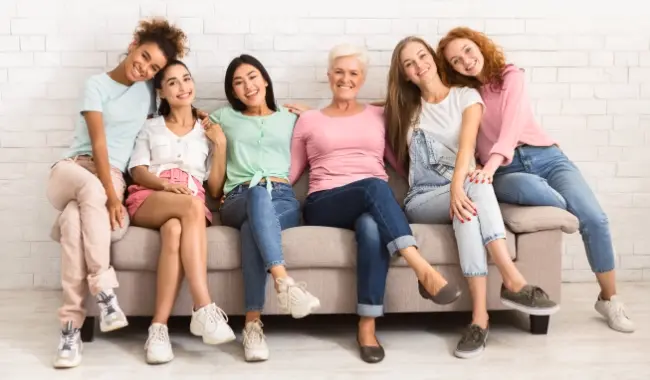 group of women smiling on sofa together, different ages