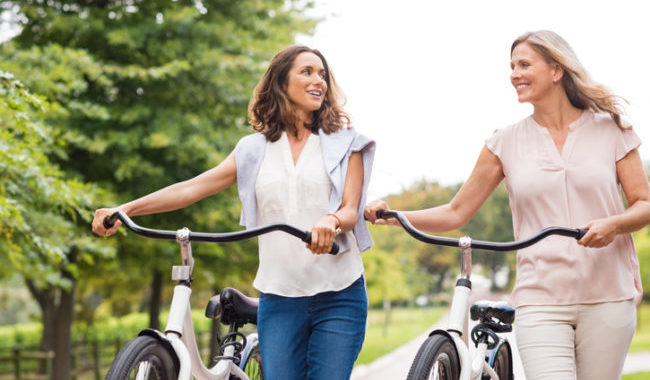 two women walking bikes talking
